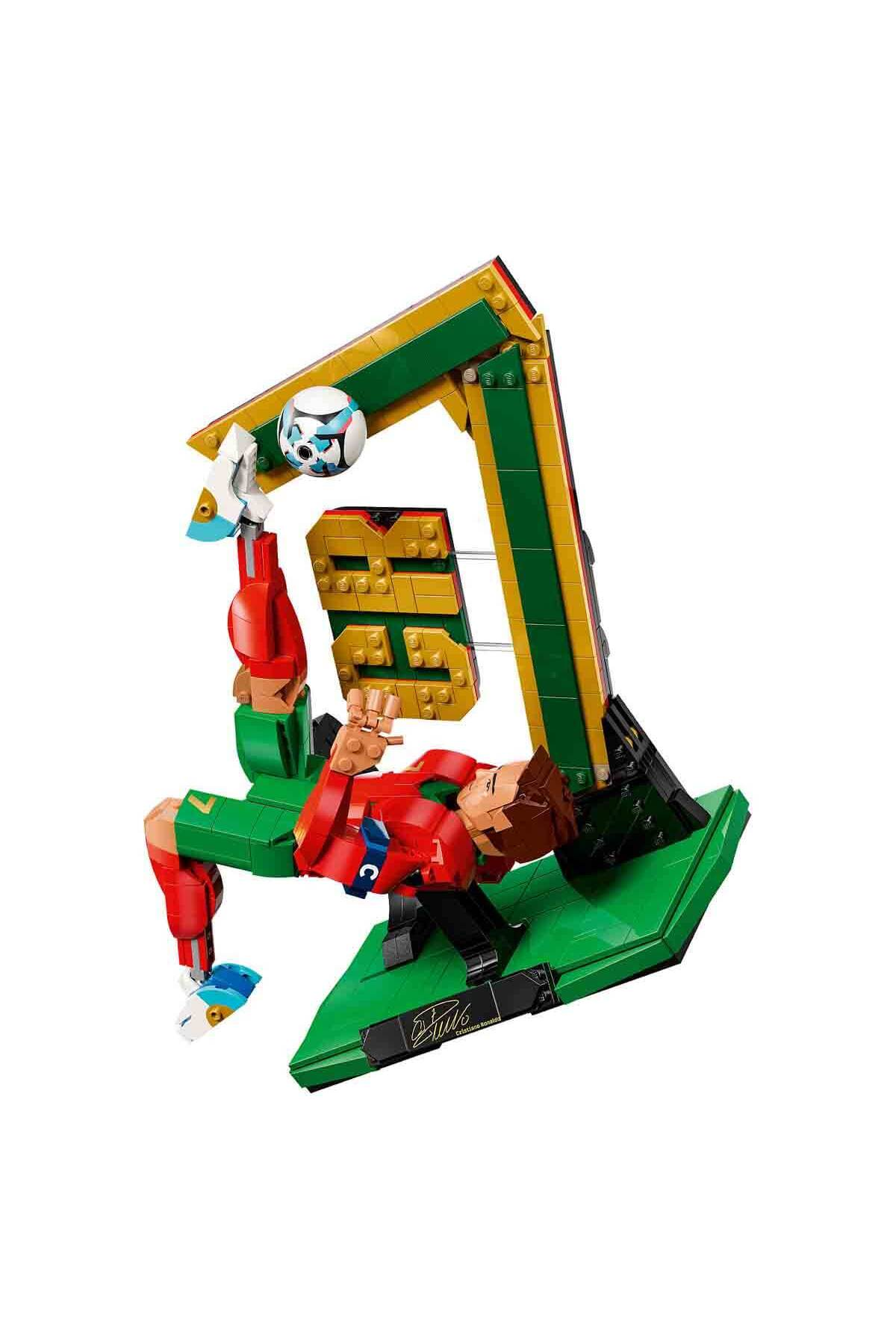 Yeşil ve kırmızı giysili Lego figürü, futbol topuyla yeşil kaleye röveşata çekiyor.