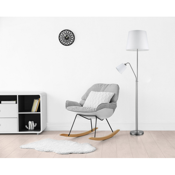 Una mecedora gris con cojín blanco, lámpara de pie y reloj moderno en una sala de estar minimalista y luminosa.