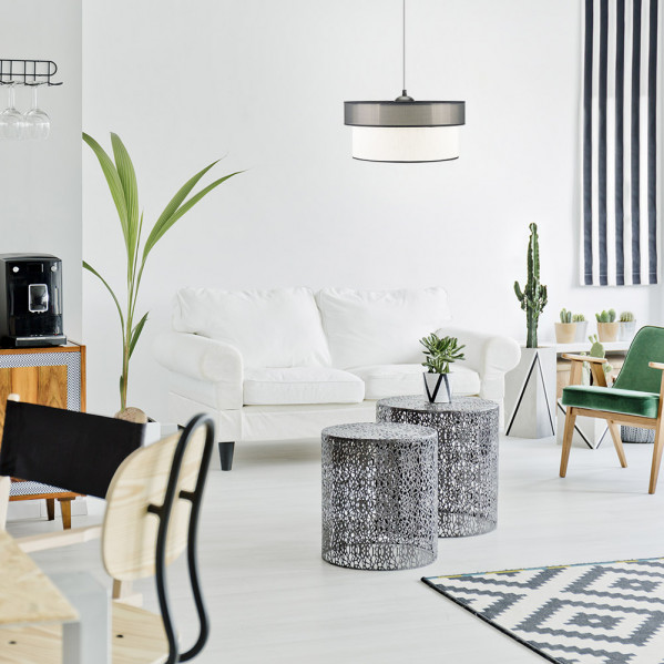 Una sala luminosa con sofá blanco, dos mesas de centro de metal, una lámpara colgante y un sillón verde.