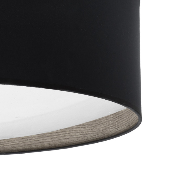 Primer plano de una pantalla de lámpara cilíndrica negra con interior blanco y borde de madera.