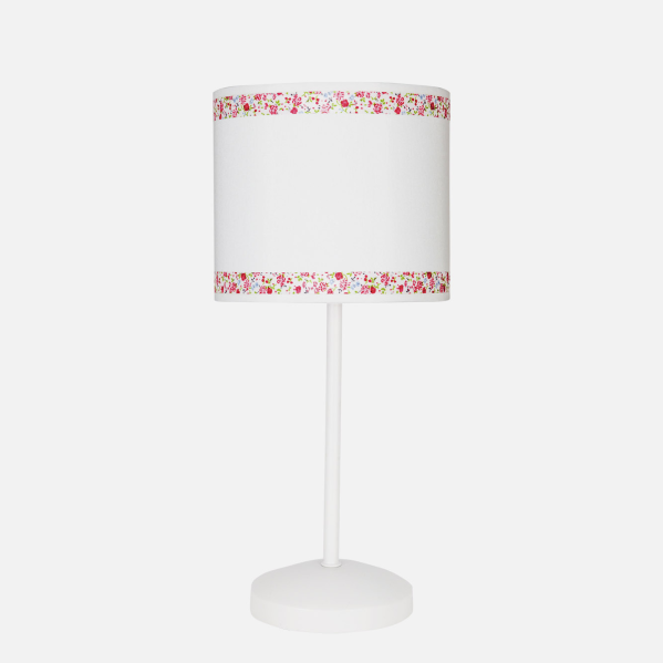 Una lámpara de mesa blanca con una pantalla con cenefas florales rojas y blancas arriba y abajo.