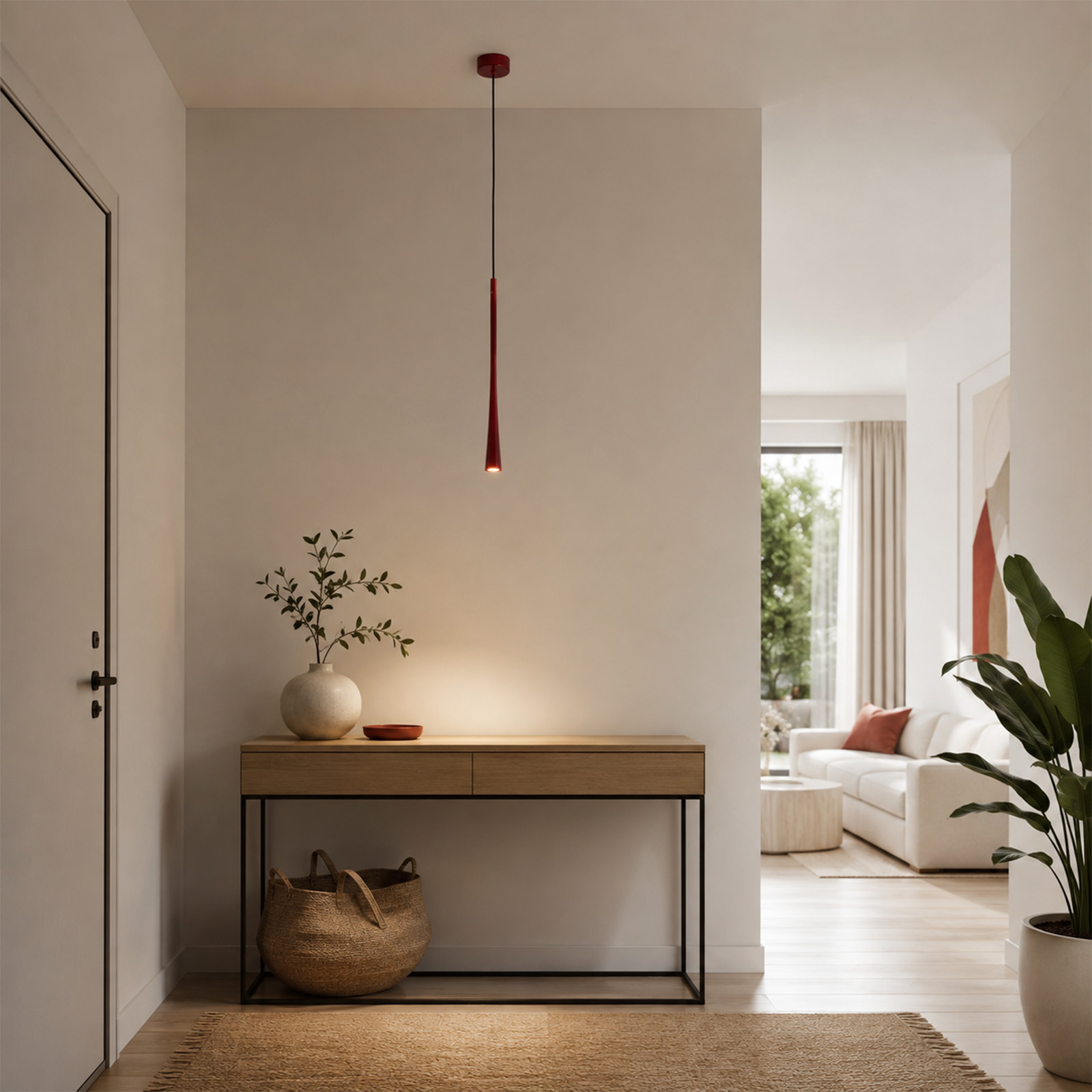 Un pasillo minimalista con consola de madera, lámpara colgante roja, jarrón y cesta. Al fondo se ve una sala de estar.