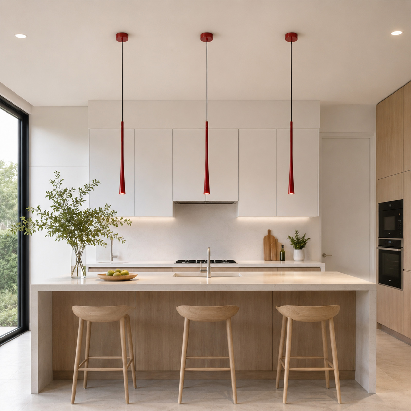 Moderna cocina con gabinetes blancos, detalles de madera, tres lámparas colgantes rojas y una isla con tres taburetes.