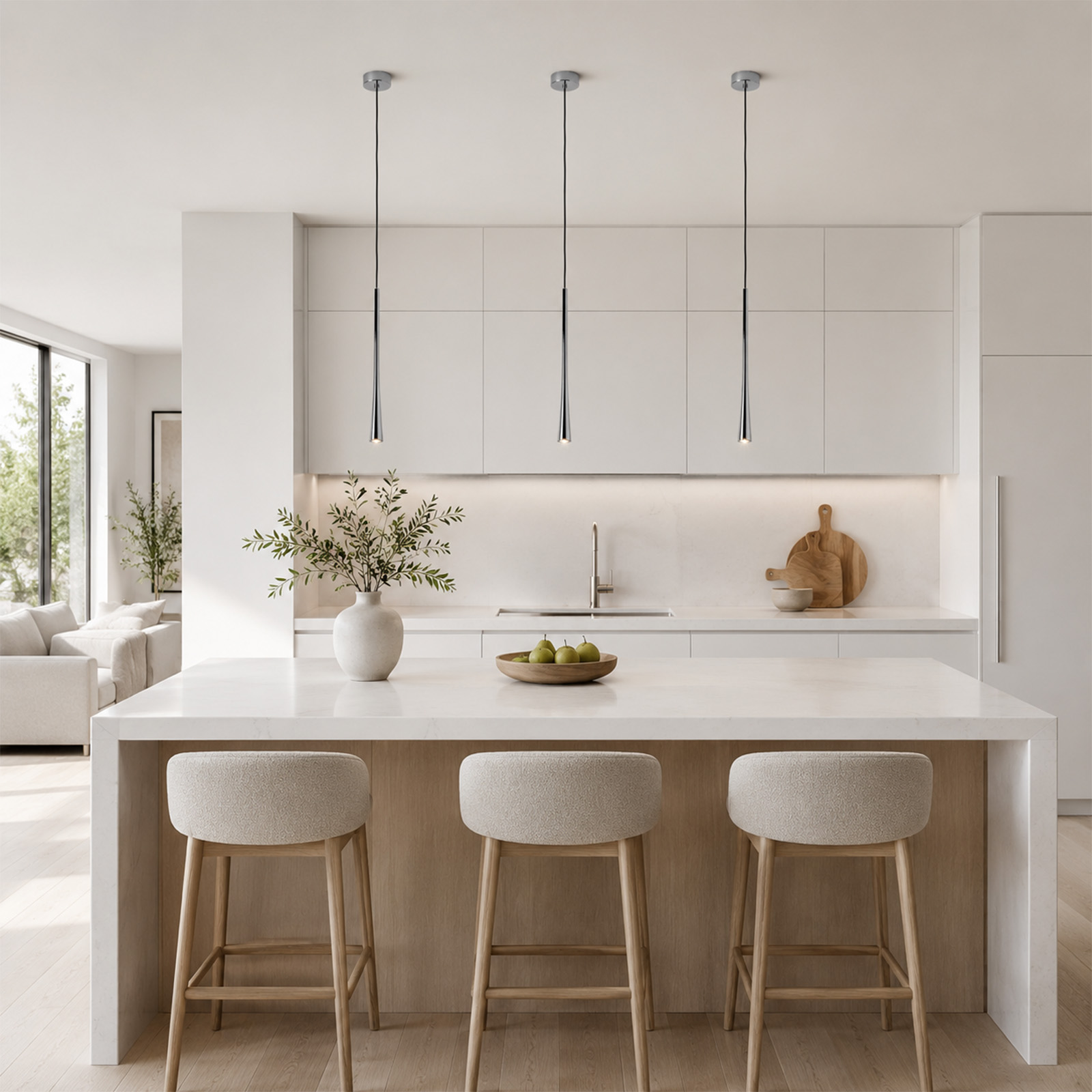 Moderna cocina blanca con isla, tres taburetes claros, lámparas colgantes y jarrón con hojas.