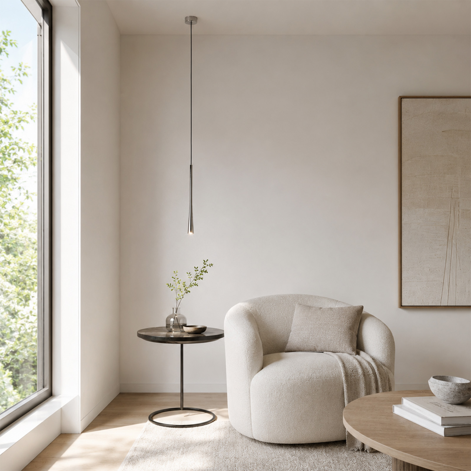 Una habitación luminosa con sillón blanco, mesa auxiliar con florero, lámpara colgante y cuadro enmarcado.