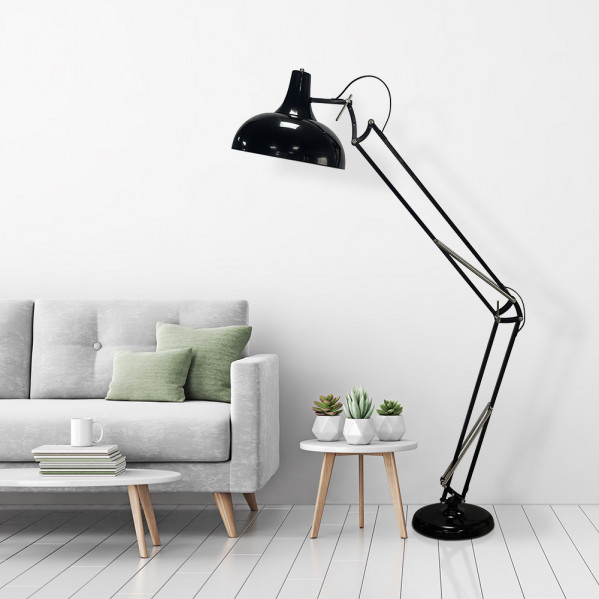 Una sala con sofá claro, cojines verdes, mesita con plantas y una gran lámpara de arco negra.