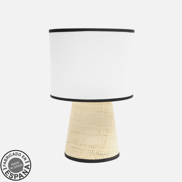 Lámpara de mesa con base de rafia beige y pantalla cilíndrica blanca con ribete negro.