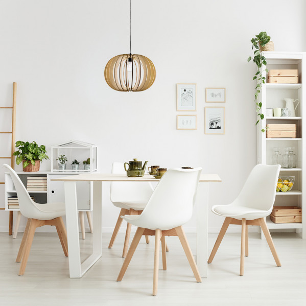 Un comedor luminoso con una mesa blanca, cuatro sillas blancas, una lámpara colgante de madera y una estantería.