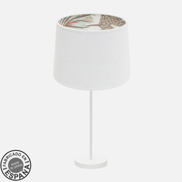 Una lámpara de mesa blanca con pantalla interior estampada y base redonda sobre fondo neutro.