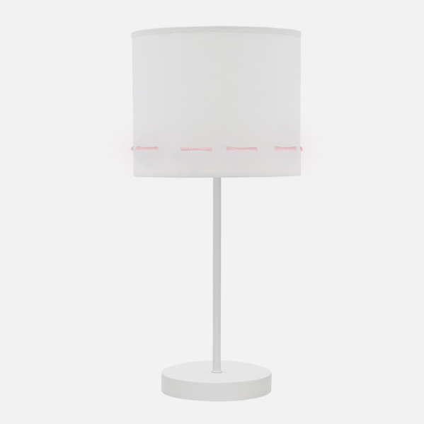 Una lámpara de mesa blanca con pantalla cilíndrica y detalles rosas sobre fondo neutro.