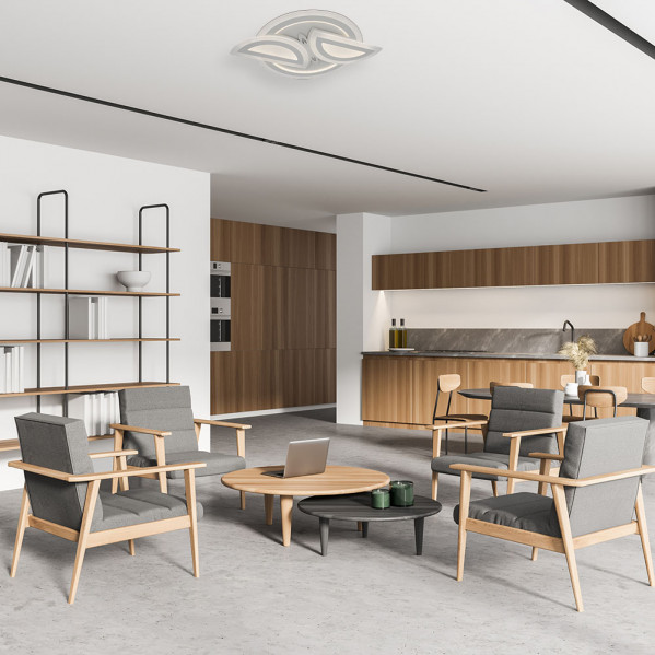 Sala de estar moderna con sillones grises, mesas de centro de madera, estantería y cocina abierta al fondo.