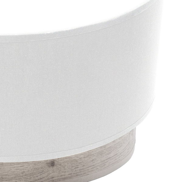 Una pantalla de lámpara redonda de tela blanca sobre una base de madera clara.
