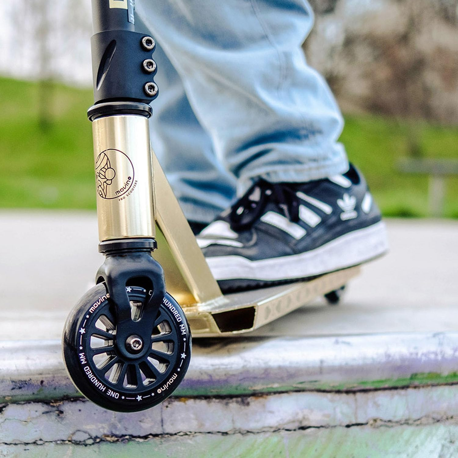 Nahaufnahme eines goldenen Stunt-Scooters mit schwarzem Rad an einer Skatepark-Kante.