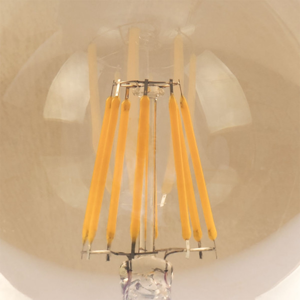 Primer plano de una bombilla LED de filamento amarillo cálido con rayas luminosas en vidrio transparente.