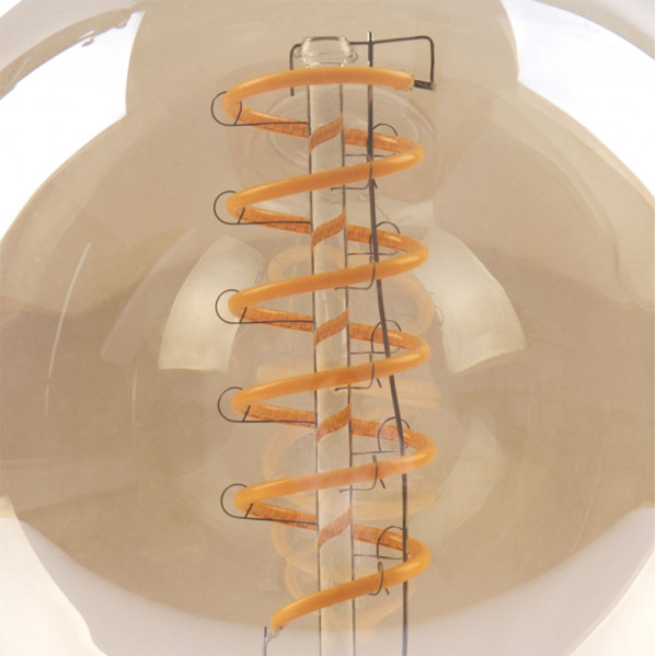 Primer plano de una bombilla grande con un filamento LED amarillo en espiral.