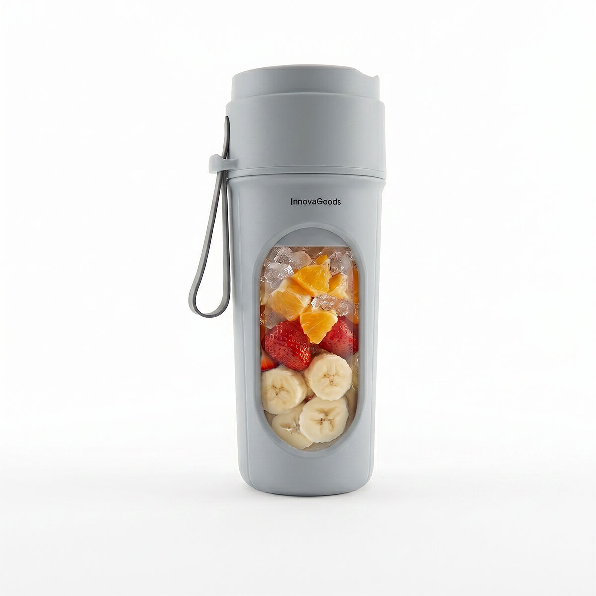 Un frullatore portatile grigio con finestra trasparente riempita di fette di banana, fragole, pezzi di arancia e ghiaccio.