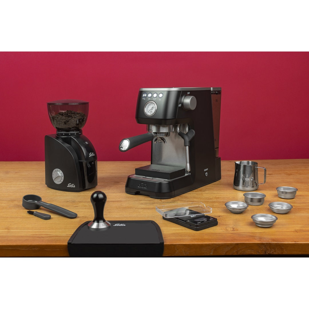 Una macchina da caffè espresso nera e un macinacaffè con accessori su un tavolo.