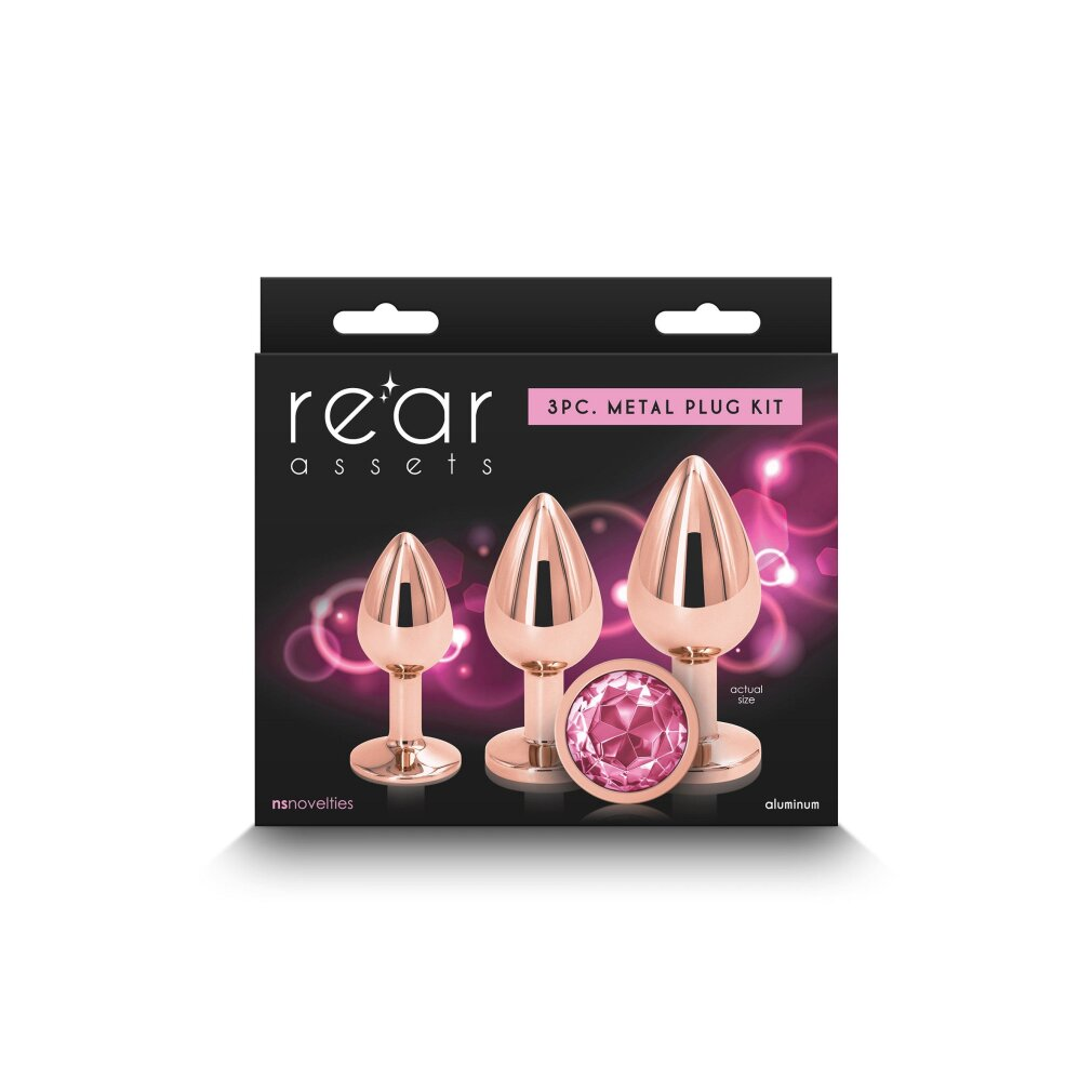 Verpackung für ein 3-teiliges Metall-Plug-Set in Roségold mit rosa Steinen auf schwarzem Hintergrund mit rosa Lichtern.