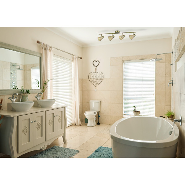 Un baño luminoso con una bañera independiente, lavabo doble, inodoro y paredes de azulejos.