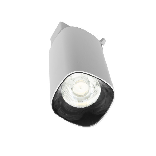Un foco plateado moderno con bombilla LED visible sobre fondo blanco.