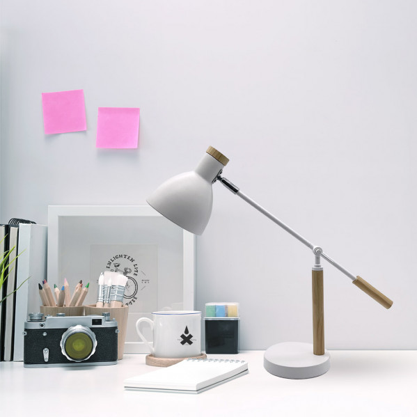 Un escritorio blanco con una lámpara, cámara, lápices, una taza y notas adhesivas en la pared.