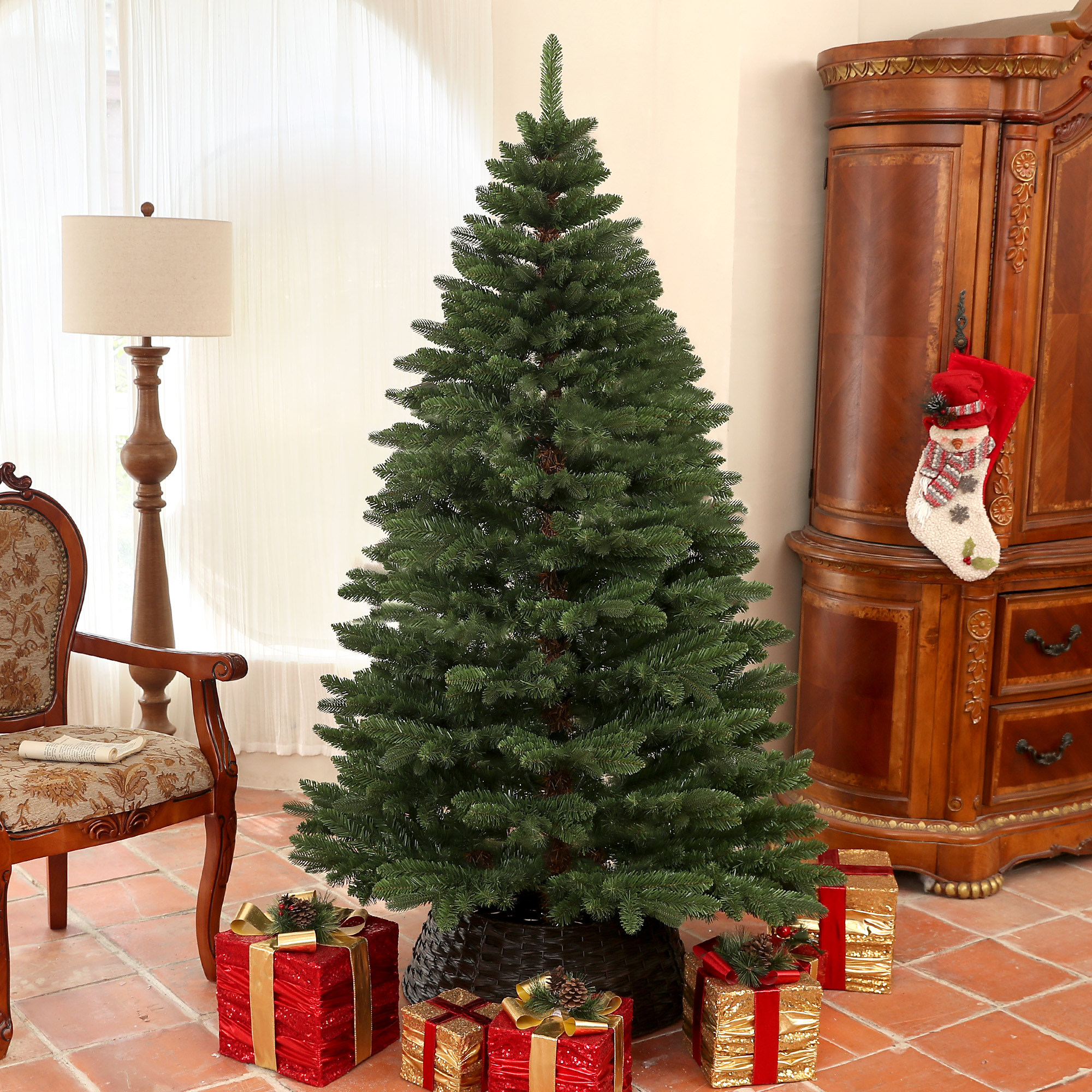 Un árbol de Navidad decorado en el interior con regalos envueltos alrededor de su base y muebles cerca.