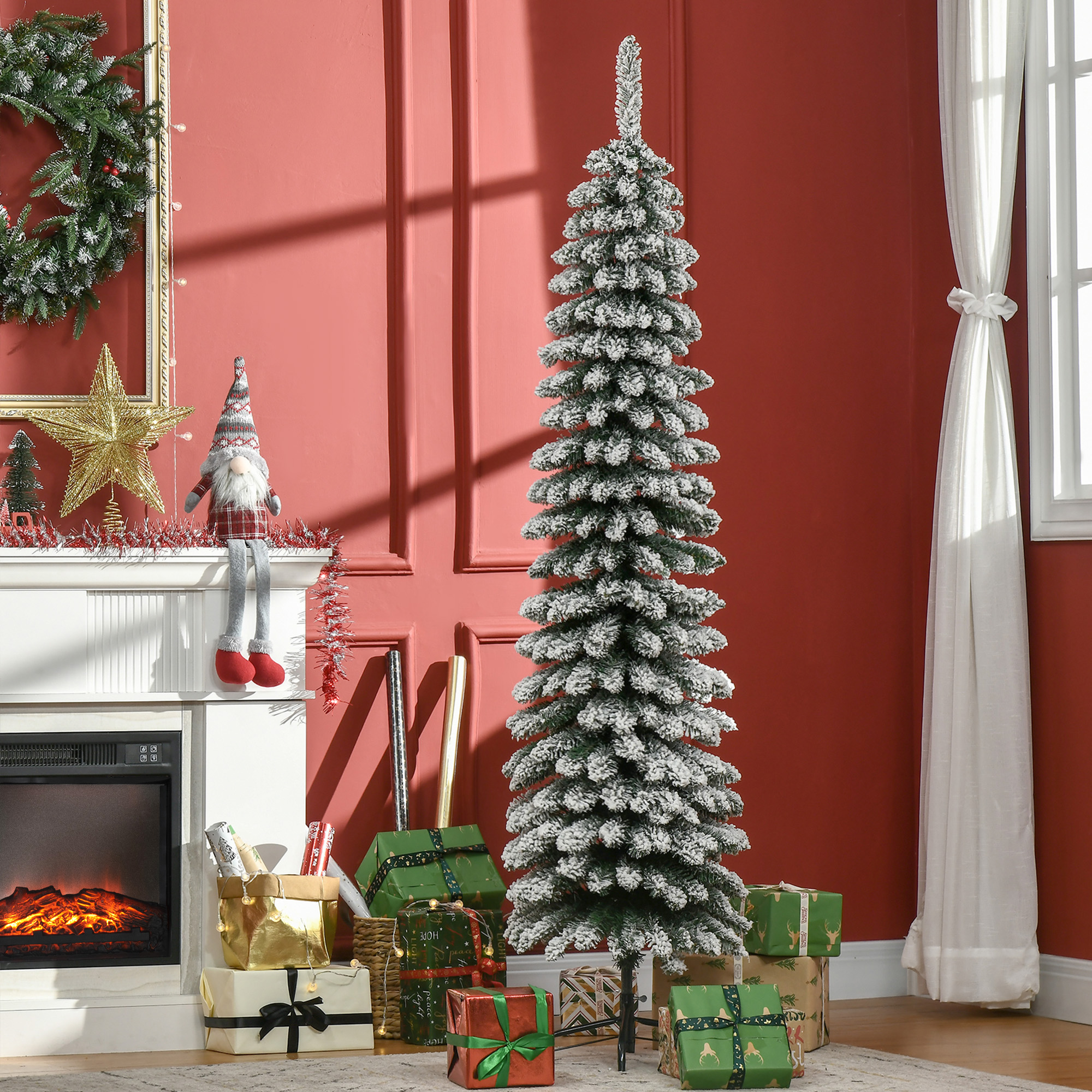Un árbol de Navidad artificial cubierto de nieve está junto a una chimenea blanca con regalos y una pared roja.