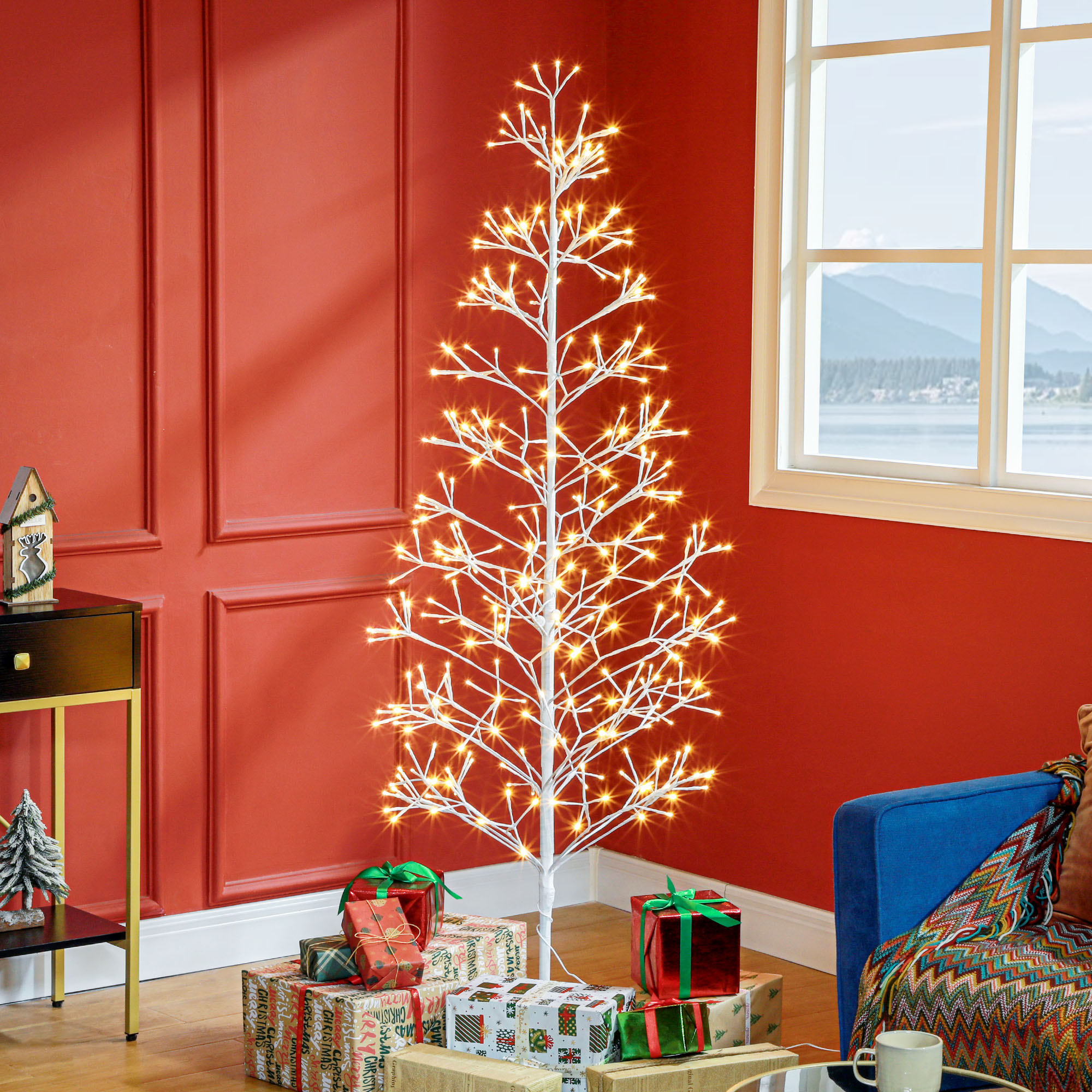 Un árbol de Navidad blanco e iluminado se encuentra en una habitación con paredes rojas y regalos.