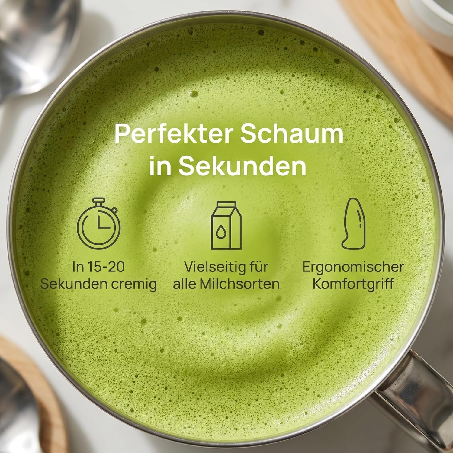 Ein schaumiges grünes Matcha-Getränk in einem Metallbecher mit deutschem Text und Symbolen.