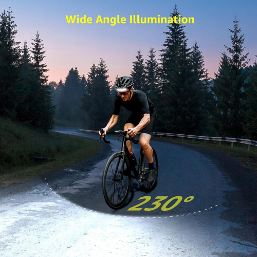 Un ciclista pedalea por una carretera sinuosa frente a un bosque de noche con iluminación amplia.