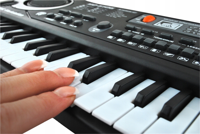 Dłoń z francuskim manikiurem gra na czarno-białych klawiszach keyboardu elektronicznego.