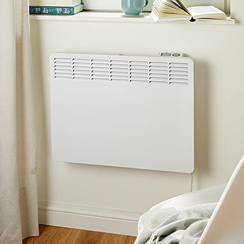 Un termosifone bianco montato su una parete sotto un davanzale con libri.