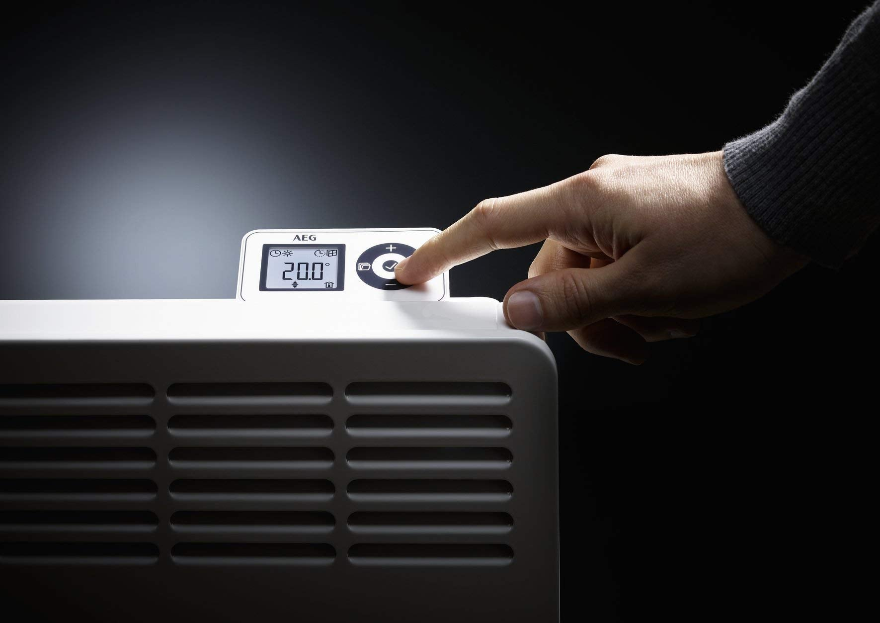 Una mano tocca il display di una stufa bianca che mostra 20,0 gradi.