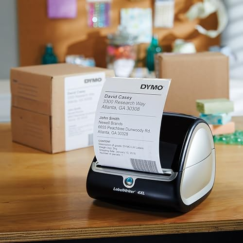 Ein DYMO LabelWriter 4XL druckt ein Versandetikett auf einem Holztisch, umgeben von Pappkartons.