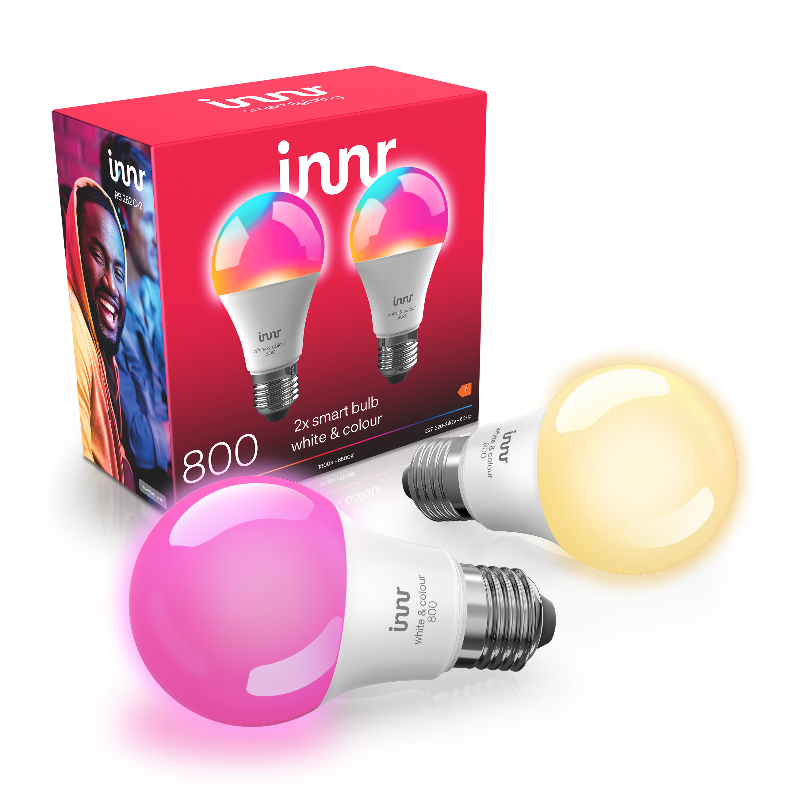 Zwei Innr Smart-Glühbirnen vor einer roten Verpackung, eine leuchtet rosa, die andere warmweiß.