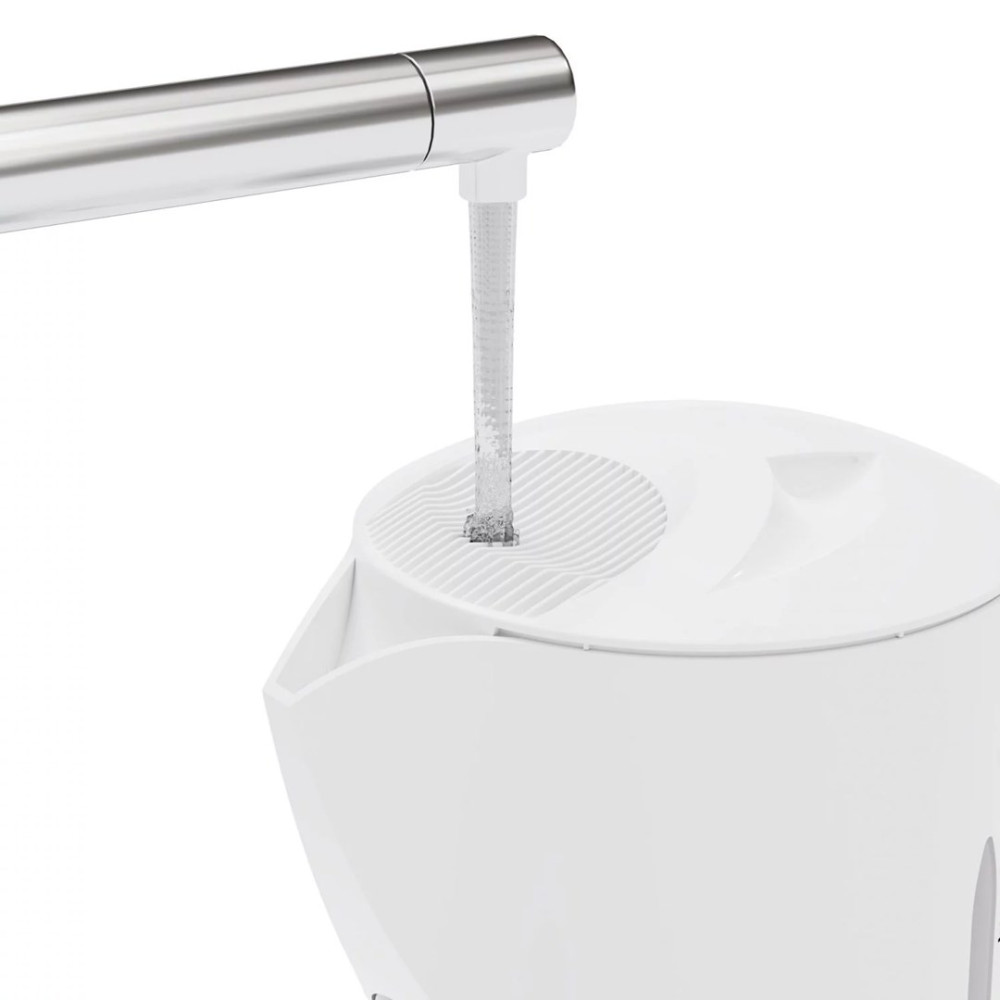L'acqua scorre da un rubinetto di metallo nel coperchio di un filtro d'acqua bianco su sfondo bianco.