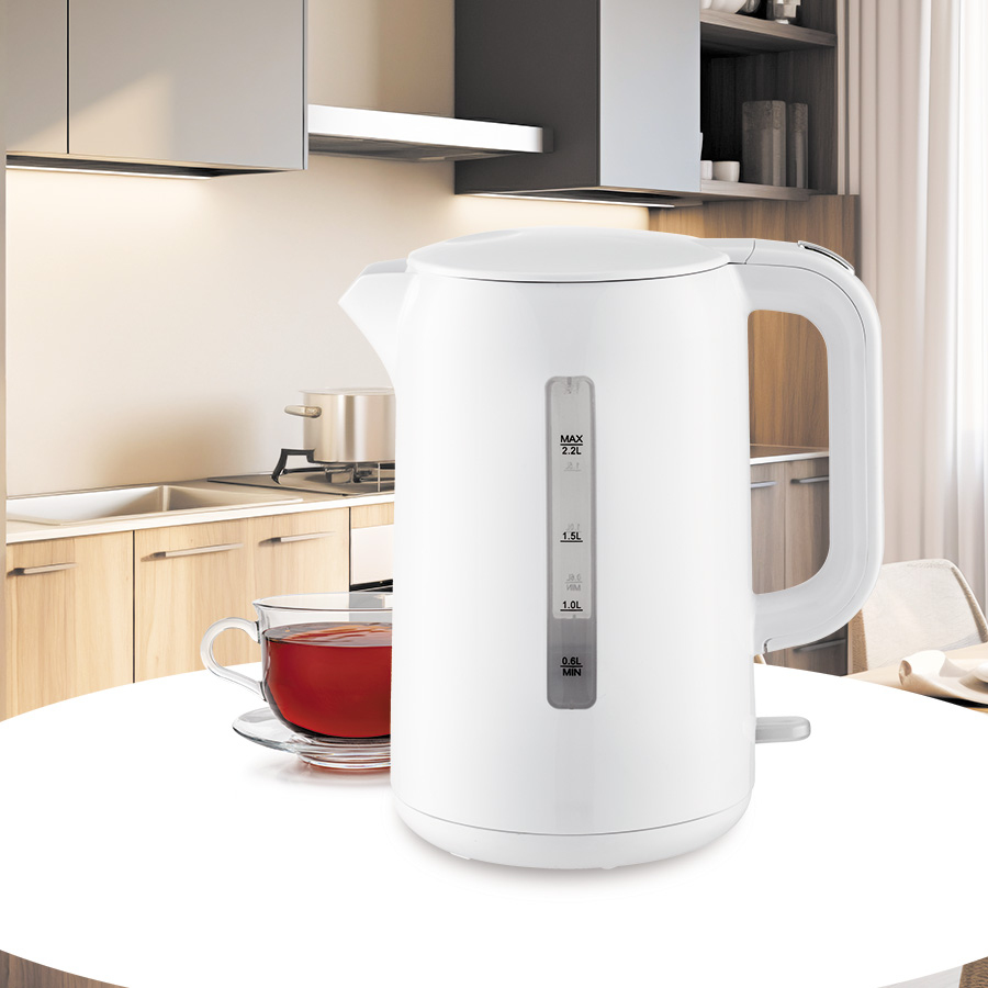 Un bollitore elettrico bianco e una tazza di tè su un tavolo bianco in una cucina moderna.