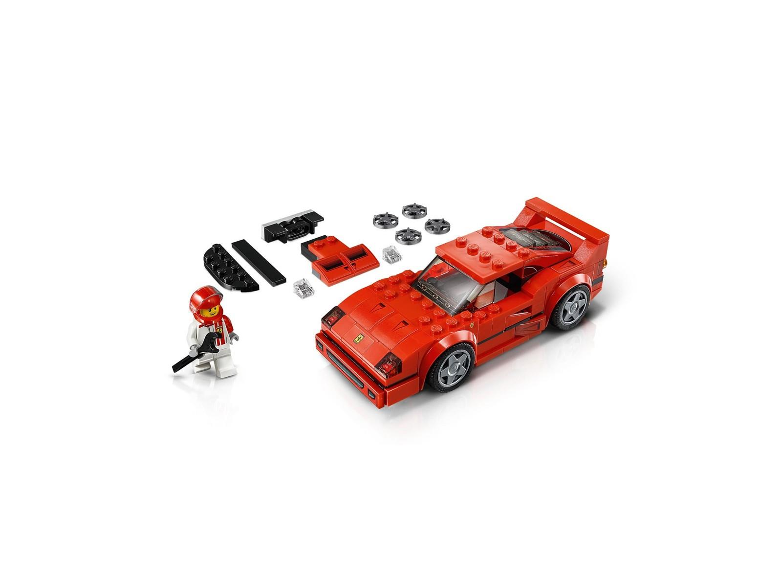 Ein rotes Lego-Spielzeugauto, eine Minifigur im Rennanzug und Ersatzteile liegen auf weißem Grund.
