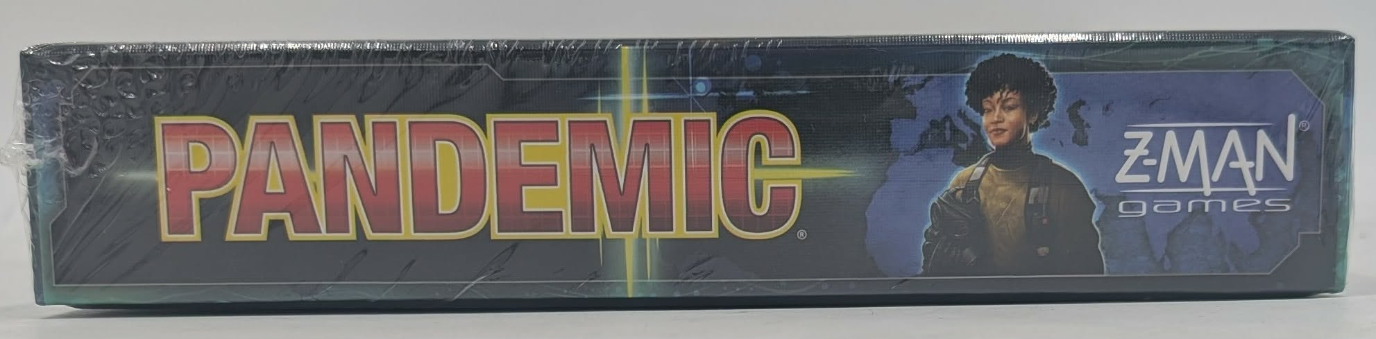 Seitenansicht der Brettspielverpackung von Pandemic mit rotem Titel und Charakterillustration vor Weltkarte.