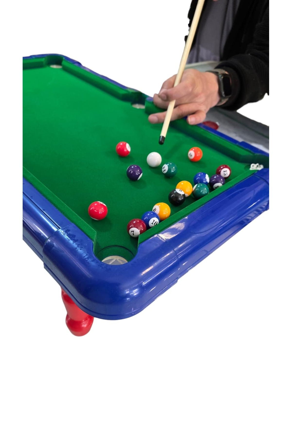 Yeşil keçeli ve renkli toplu mavi bir mini bilardo masasında oynayan bir kişi.