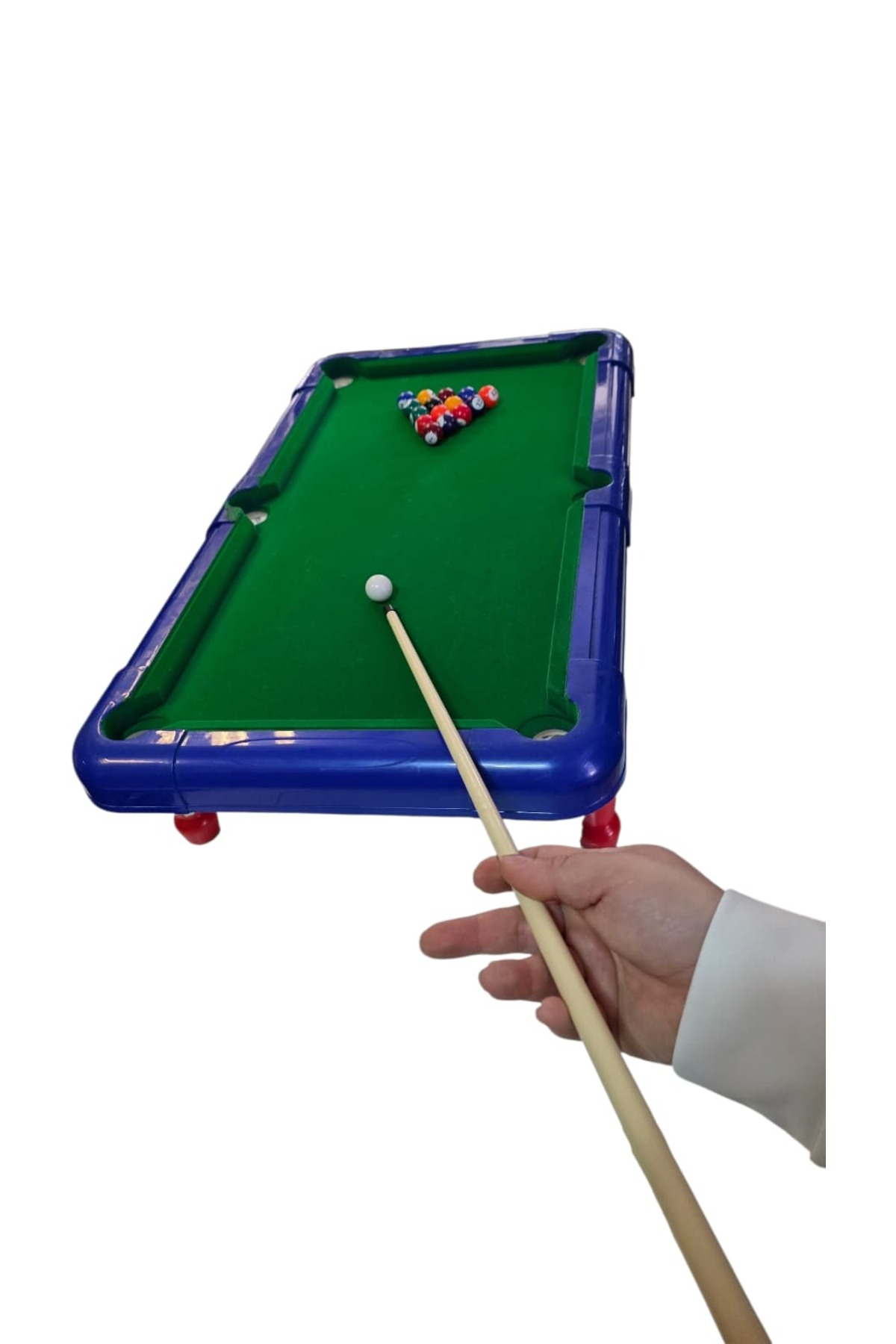 Bir el, yeşil çuhalı ve toplu küçük mavi bilardo masasının üzerinde bir istaka tutuyor.