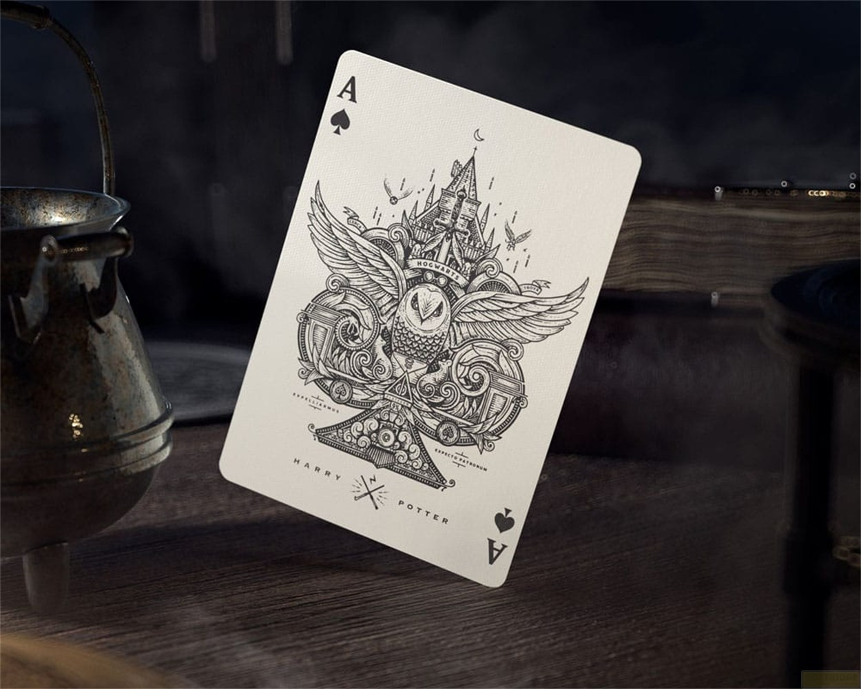 Une carte d'as de pique sur le thème de Harry Potter sur une table en bois, près d'un chaudron rouillé.