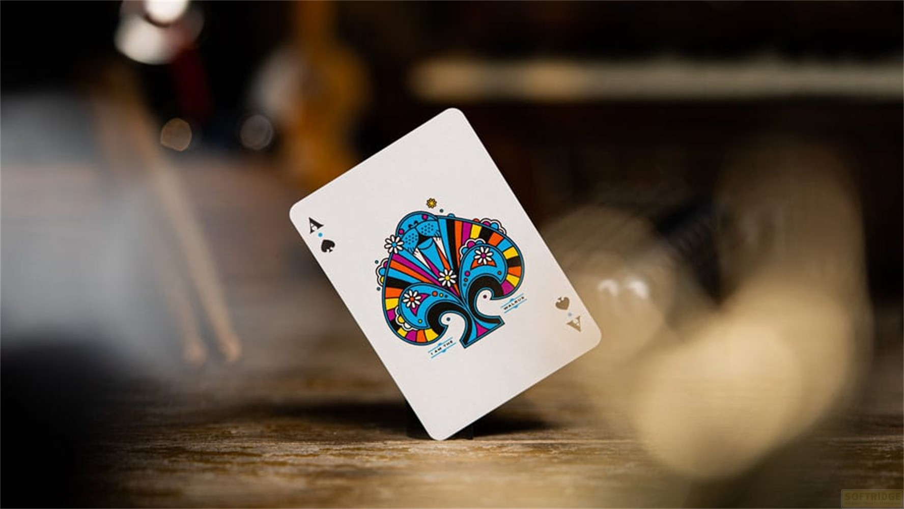 Une carte à jouer As de Pique colorée posée sur du bois avec un fond flou.