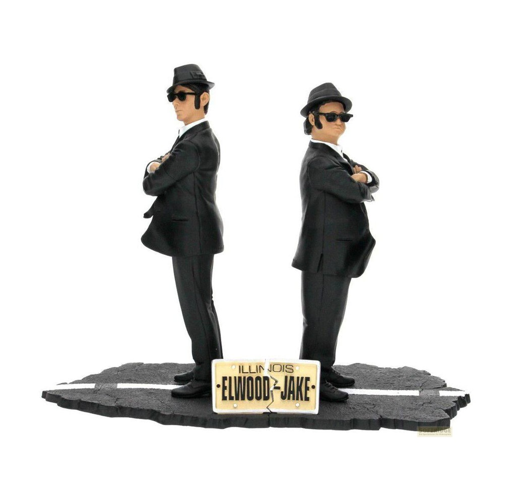 Las figuras de los Blues Brothers están de espaldas con trajes negros, sombreros y gafas de sol sobre una base.