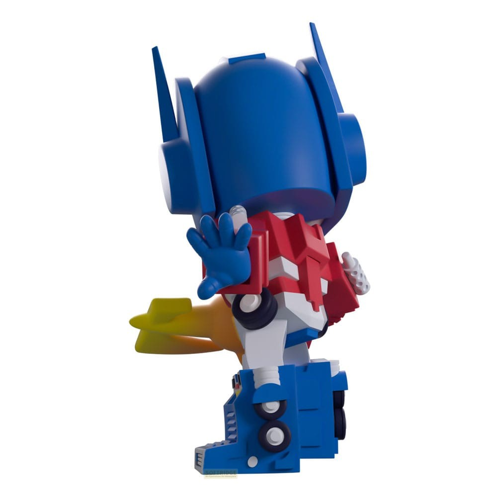 Vista trasera de una figura de Optimus Prime en rojo, azul y blanco, sosteniendo un arma amarilla sobre fondo liso.