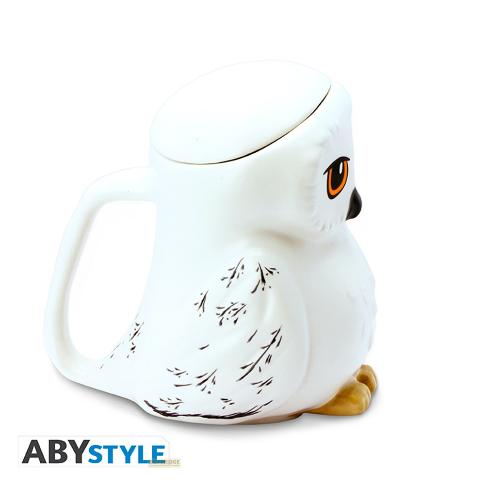 Una tazza in ceramica bianca a forma di gufo con coperchio, occhi arancioni e dettagli di piume nere su sfondo bianco.