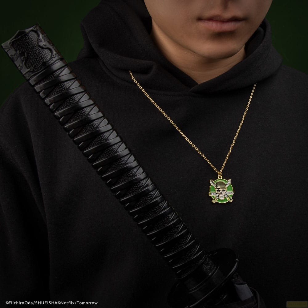 Una persona con sudadera negra lleva un collar de calavera y una vaina de espada negra sobre su pecho.