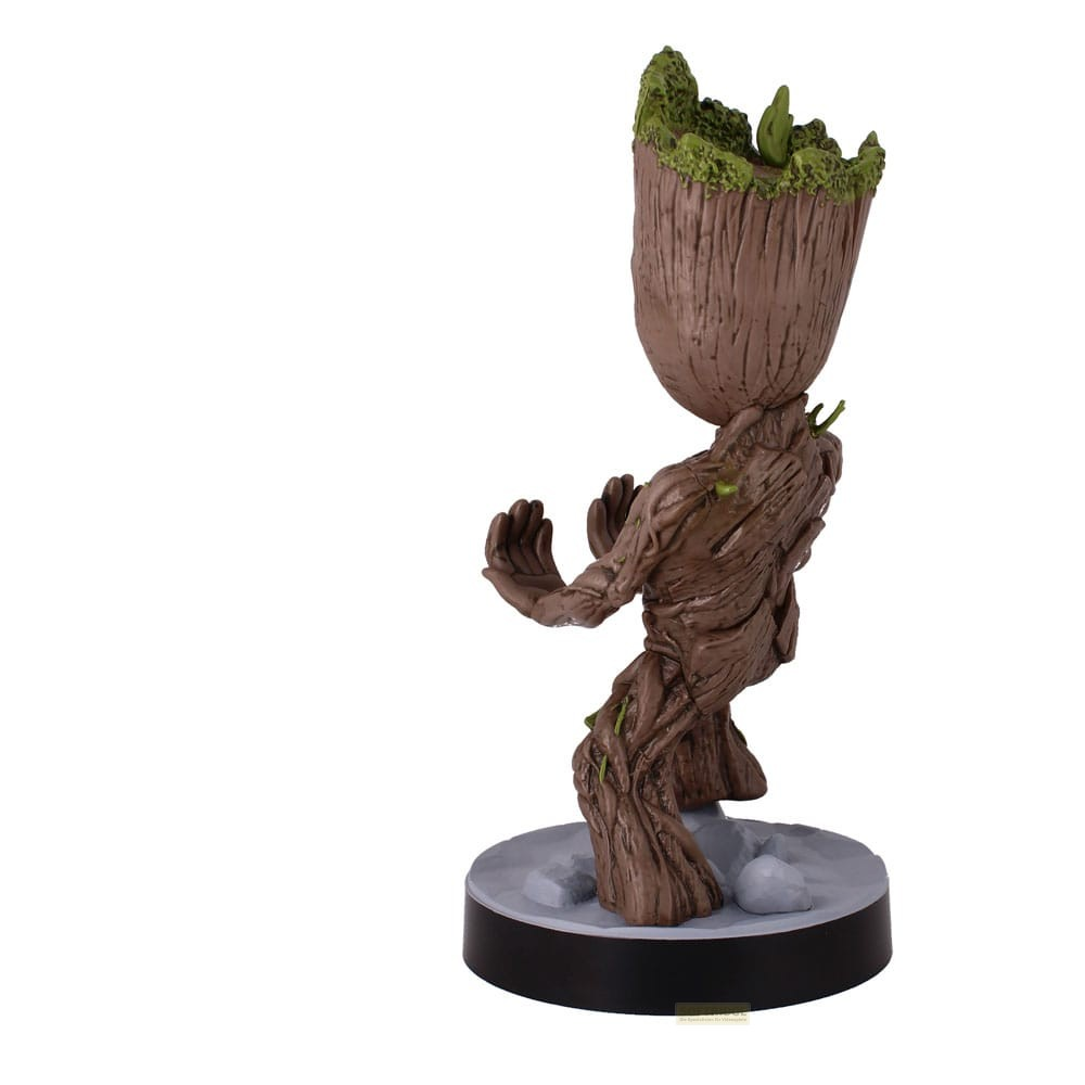 Una statuetta di legno di Groot con muschio verde sulla testa si erge su una base grigia.