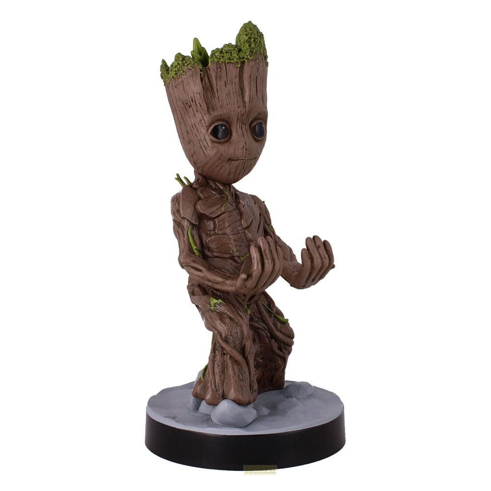 Una statuetta di Baby Groot in legno con grandi occhi neri in piedi su una base rotonda grigia.