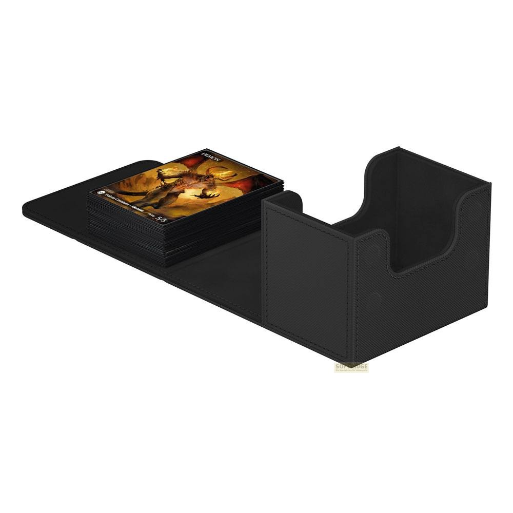 Boîte de deck de cartes en cuir noir avec une pile de cartes illustrées fantastiques à côté sur un tapis.
